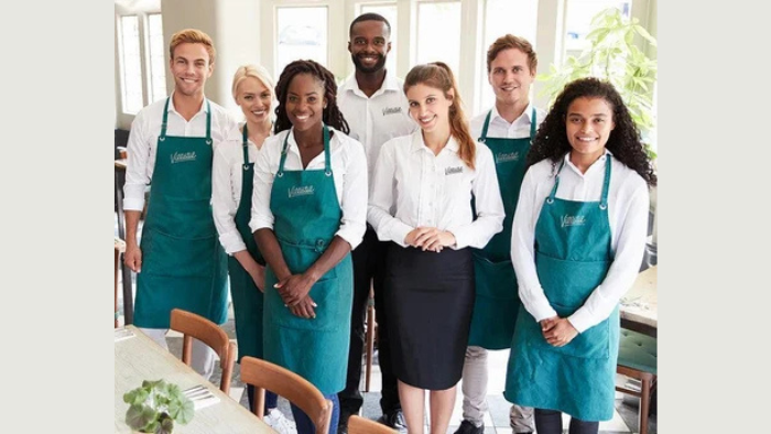 A team of people with embroidered aprons and button-downs